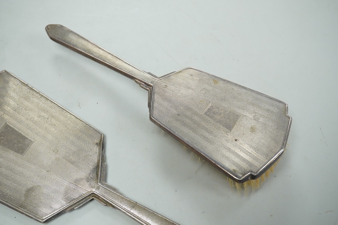 An Elizabeth II engine turned silver Art Deco style four pieced dressing table mirror, brush and comb set, W.I. Broadway & Co, Birmingham, 1961/63/65, mirror 27.8cm.